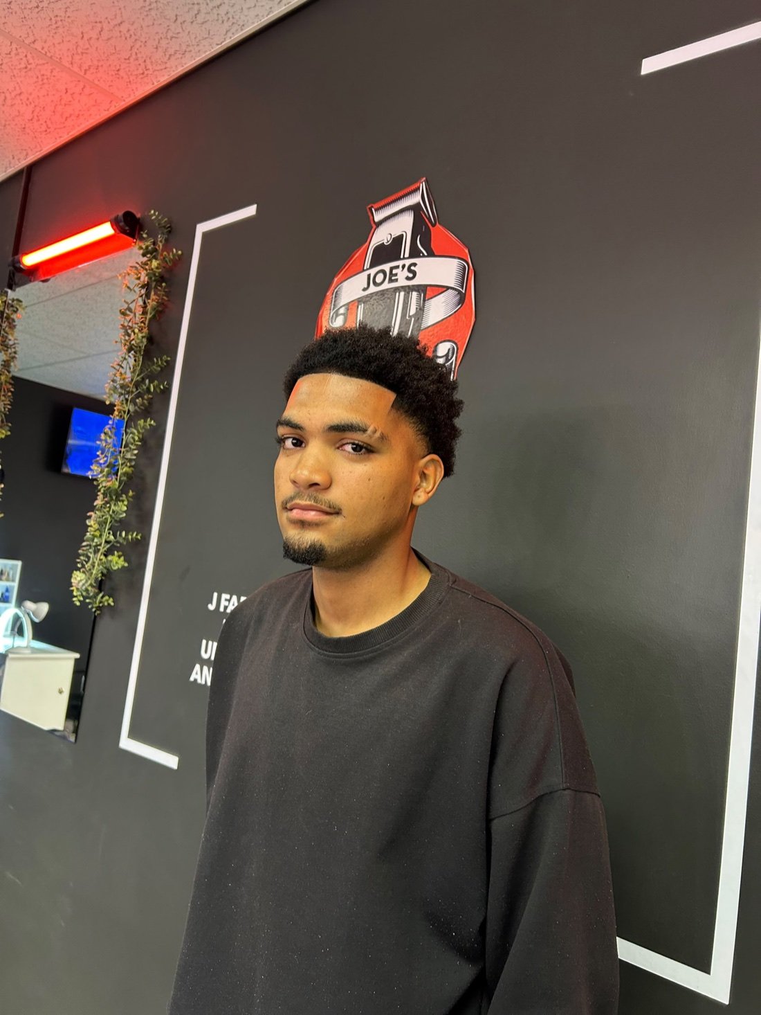 Fresh fade in front of the Joe's Fade Cuts branded wall